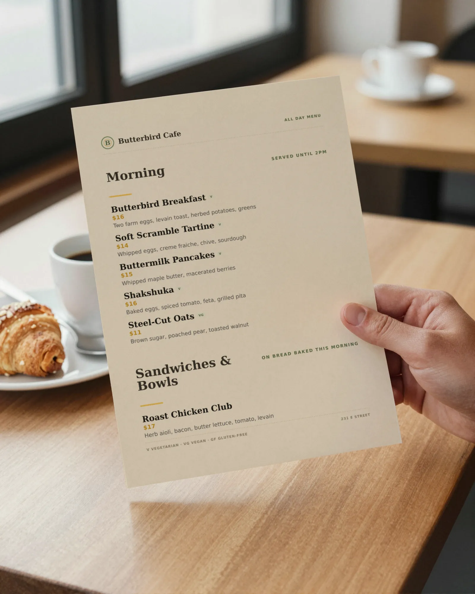 A hand holding a printed café menu at a sunny table